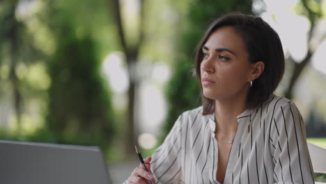 Pensive-woman-Brunette-Hispanic-ethnic-group-sits-at-a-table-in-a-summer-cafe-with-a-laptop.-Serious-business-woman-pondering-problem-solving-and-business-development-strategy